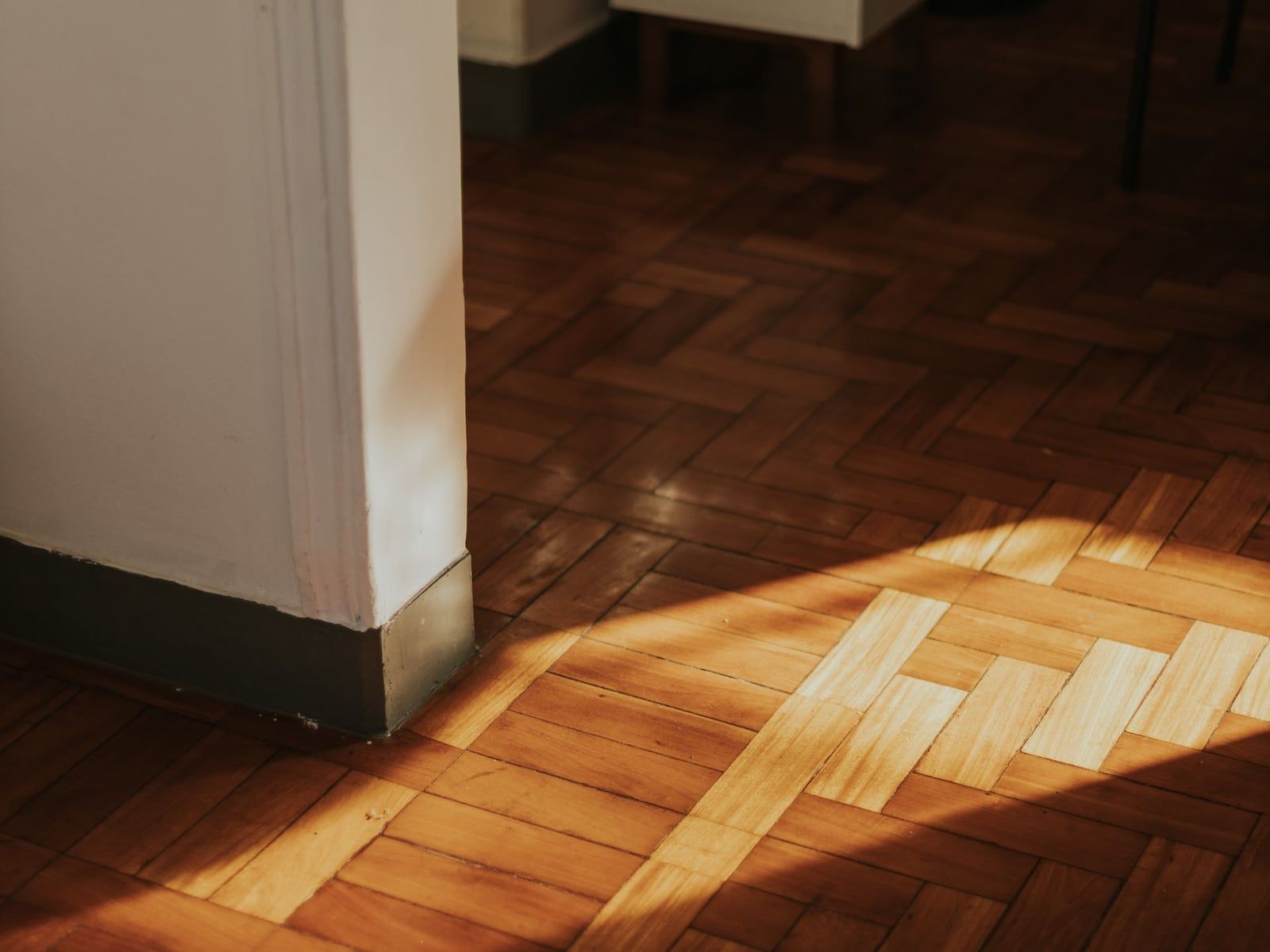 Sunlight on an oak parquet floor next to a white wall